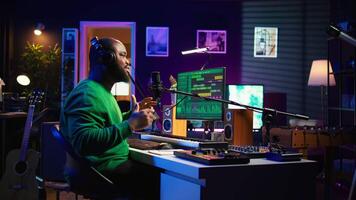 Artist producer singing a new song to record on microphone, preparing to edit music in post production. Musician expert applying mixing and mastering techniques on his audio recorded files. Camera B. video