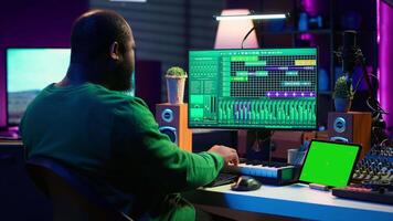 Artist producer creating new music with mix and master techniques, using a screen with copy space layout. Skilled audio engineer editing tracks in post production, digital audio software. Camera A. video