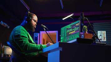 African american music producer twisting knobs on mixing console, produce tracks with sound effects. Artist composing songs in post production, operates on digital software in home studio. Camera B. video