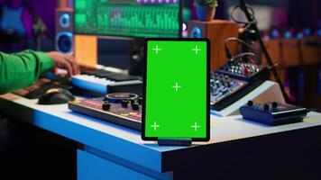 Composer editing his audio files and recordings on daw software, sitting next to a green screen display. Skilled sound technician uses mixing and mastering gear to produce new material. Camera A. video