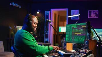 Audio engineer working in home studio with digital software on pc, playing piano keys and editing audio recordings. Musician producer creating tracks on midi controller keyboard notes. Camera B. video