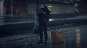 A traveler looks at a map on a train platform, hinting at a journey or adventure video