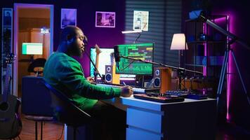 Songwriter taking notes to create new tracks for an album in his home studio, writing lyrics and harmonic elements before recording his song and editing on software, acoustical engineering. Camera B. video