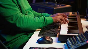 Young songwriter playing piano and singing on microphone, recording his new music and mixing the tunes on digital software. Musician composer producing soundtracks with modern gear. Camera A. video