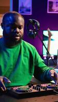 Vertical Skilled audio engineer teaching online mixing tunes lessons by using smartphone on tripod to record himself in home studio. Producer hosting a master class with soundboard console gear. Camera B. video
