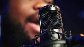 Artist records his voice on microphone in home studio singing a song composed by him. Skilled musician using recordings and lyrics to edit in post production, mixing and mastering session. Camera B. video
