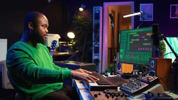 Modern producer playing piano keys to record new soundtrack, trying to produce song using midi controller electronic keyboard. Songwriter composer playing instrument notes to create tunes. Camera B. video