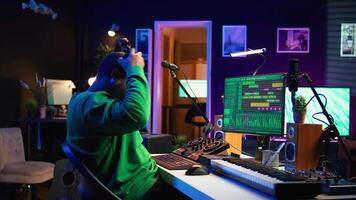 Confident music engineer working on mixing console in home studio, producing new sounds for a song and editing volume levels in daw software. Audio technician recording acoustic files. Camera B. video