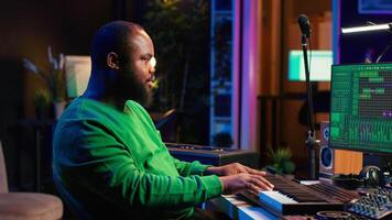 Musician playing piano keyboard and recording tracks for mix and master session, using digital software on pc to create new songs. Sound producer composing music with midi controller tool. Camera A. video