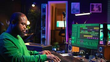 Sound engineer pressing keys of electronic synthesizer and composing new song, adjusting volume levels on pre amp knobs. Composer producing music on piano midi controller, mixing tunes. Camera B. video