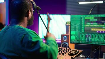 Confident music engineer working on mixing console in home studio, producing new sounds for a song and editing volume levels in daw software. Audio technician recording acoustic files. Camera A. video
