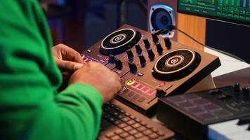 Music technician with headset mixing and mastering his audio recordings, operating on console in home studio. Musician producer creating new tunes with sound effects in post production. Camera A. video