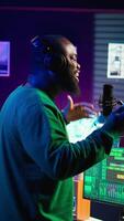 Vertical Young artist singing his new song creation on microphone gear, editing his recordings to adjust volume levels with mix and master techniques. Singer composing a melody, stereo tools. Camera B. video