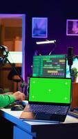 Vertical Producer editing his audio files and recordings on digital pc interface, sitting next to an isolated mockup screen. Sound engineer mixing and mastering songs with console in home studio. Camera B. video