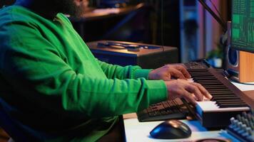 Music composer plays electronic keyboard piano keys and recording new tracks, creating audio recordings before launching music. Artist producer uses synthesizer, post production. Camera A. video