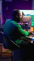 Vertical Audio engineer recording and producing new tunes on professional pc software, using mixing console and midi controller to create new music. Artist composer uses stereo gear at home studio. Camera B. video