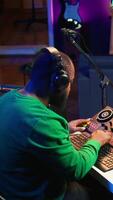 Vertical Talented musician creating new soundtracks on mixing console, operating on audio equipment in home studio. Sound technician twisting knobs to edit volume levels on his melody. Camera B. video