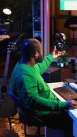 Vertical Artist composer recording a new track on his home studio microphone, editing his song with professional gear. Adjusting volume levels and adding sound effects, mix and master. Camera B. video