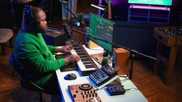Young artist playing piano keys and singing song on microphone, composing his new music and mixing the tracks on digital interface. Producer technician composing melody with gear. Camera B. video