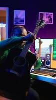 Vertical Professional composer teaching guitar lessons online on master class, recording himself playing acoustic instrument accords and explaining notes for tutorial. Young musician making vlogs. Camera B. video