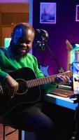 Vertical Guitarist instructor hosting guitar lessons online using a mobile phone, recording tutorial for master class. Artist musician explains acoustic instrument accords, assistance for beginners. Camera B. video