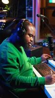 Vertical Talented famous composer writes down new verses and lyrics in home studio, composing music with digital software. Artist songwriter works with audio equipment and gear, recording tracks. Camera B. video