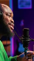 Vertical Confident artist singer performing a song on microphone in home studio, recording his audio files and manipulating raw sound on professional editing software. Music production. Camera A. video