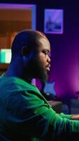 Vertical Skilled music producer creating new songs on midi controller synthesizer, working with mixing console and professional software on pc. Artist using piano and mastering acoustical tunes. Camera B. video