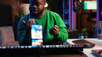 Musician doing online paid classes to help people play piano notes, teaching lessons from his home studio and recording tutorials. Musical instructor playing midi controller keyboard. Camera A. video