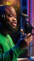 Vertical Male composer recording his melody on microphone in home studio, singing a song of his own creation. Talented artist using audio files and lyrics to apply mixing and mastering techniques. Camera A. video