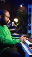 Vertical Male artist producing music on electronic piano keyboard in home studio. Sound engineer playing MIDI controller, recording and composing a soundtrack with acoustic tools and gear. Camera B. video