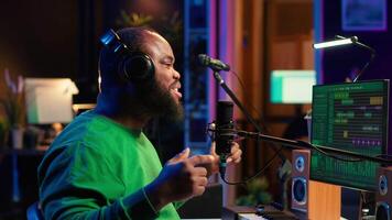 Confident songwriter performing a tune on microphone in home studio, recording his song and editing in post production. Performer artist singing aloud and using stereo equipment. Camera A. video