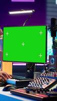 Vertical Songwriter operates on synthesizer piano keys next to isolated display, composing new music with instruments and stereo tools in home studio. Artist producer works with green screen. Camera B. video