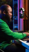 Vertical Audio engineer recording and producing new tunes on professional pc software, using mixing console and midi controller to create new music. Artist composer uses stereo gear at home studio. Camera A. video