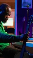 Vertical Creative songwriter singing a melody and playing guitar, signal processing technology with digital audio software. Artist producer creating music with acoustic instrument and console. Camera A. video