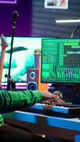 Vertical Sound engineer pressing keys of electronic synthesizer and composing new song, adjusting volume levels on pre amp knobs. Composer producing music on piano midi controller, mixing tunes. Camera A. video
