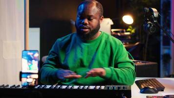 Famous piano teacher conducting internet master class via vlog tutorial, teaching people how to hit the right notes on electronic keyboard. Young artist performer hosts synthesizer lessons. Camera A. video
