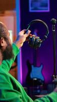 Vertical Sound producer working with console and electronic keyboard to create perfect tracks for his songs, recording and editing audio. Music composer adjusts volume levels on pre amp knobs. Camera A. video