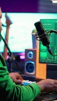 Vertical Young artist playing piano keys and singing song on microphone, composing his new music and mixing the tracks on digital interface. Producer technician composing melody with gear. Camera A. video