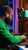 Vertical African american composer creating a new track for a project, using professional production pc interface in his home studio. Creative artist songwriter producing music with sound effects. Camera A. video