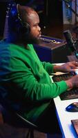 Vertical Young artist playing piano keys and singing song on microphone, composing his new music and mixing the tracks on digital interface. Producer technician composing melody with gear. Camera B. video