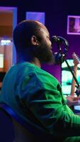 Vertical African american artist composing a new soundtrack for a project, using professional production software in home studio. Skilled creative singer producing music and adding sound effects. Camera B. video
