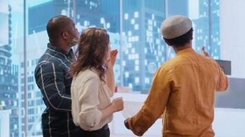 Corporate team reviewing architectural plans for a new office, discussing the building layout and the blueprints, potential investment opportunity in real estate during an office tour. Camera B. video