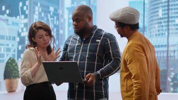 Real estate broker presenting a new high class office space to clients, discussing blueprints using a tablet during the office tour. Planning investment strategy involving property. Camera B. video