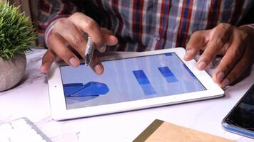 man's hand working on digital tablet at office desk, using self created chart video