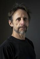 Man in Black Shirt Poses With Serious Expression Against Dark Background photo