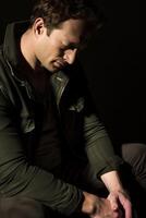 Man in Jacket Sitting Thoughtfully in Low Light photo