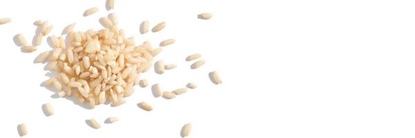 A top view of raw brown and white rice, forming a heap. The integral, uncooked grains highlight diverse Asian cuisine in this isolated pile. Horizontal banner photo