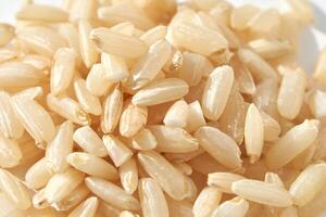 A background of dry brown rice grains showcases the integral, uncooked basmati texture. The macro view highlights the raw nature of this organic, whole food. photo