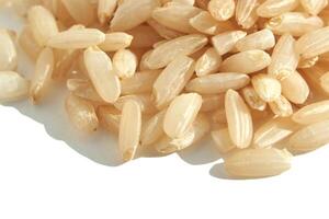 A background of dry brown rice grains showcases the integral, uncooked basmati texture. The macro view highlights the raw nature of this organic, whole food. photo